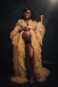 a pregnant woman in a golden gown posing for a photo